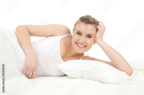 Photo: smiling beautiful girl relaxing in white bedding smiling beautiful girl relaxing in white bedding