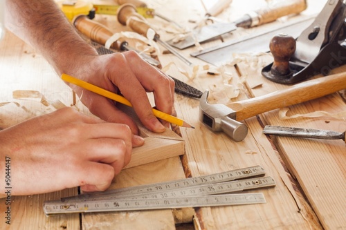 Photo: carpenter working,hammer and meter on construction background carpenter working,hammer and meter on construction background