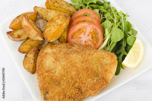 Photo: Wiener Schnitzel - Breaded fried veal, potato wedges and salad. Wiener Schnitzel - Breaded fried veal, potato wedges and salad.
