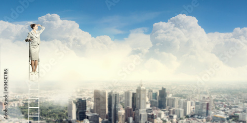 Photo: Businesswoman standing on ladder Businesswoman standing on ladder