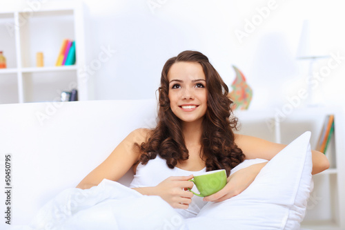 Photo: Young woman having cup of tea at home Young woman having cup of tea at home