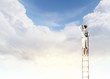 Businesswoman standing on ladder