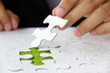 Hand embed missing puzzle piece into place, green space concept