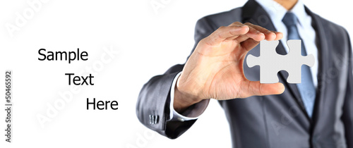 Photo: Businessman showing a piece of puzzle Businessman showing a piece of puzzle