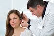 Doctor ENT checking ear with otoscope to woman patient
