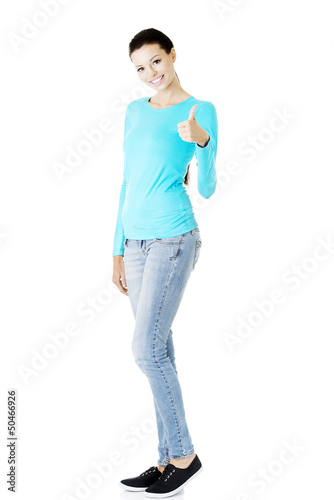 Photo: Young woman in casual clothes gesturing thumb up. Young woman in casual clothes gesturing thumb up.