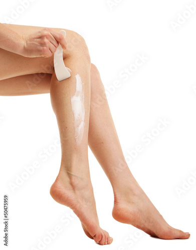 Photo: Beautiful woman legs with depilation cream, isolated on white Beautiful woman legs with depilation cream, isolated on white