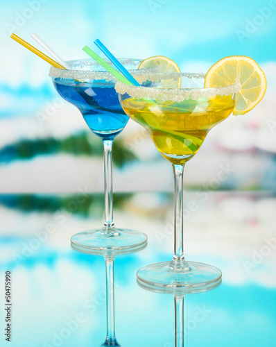Photo: Yellow and blue cocktails in glasses on blue natural background Yellow and blue cocktails in glasses on blue natural background