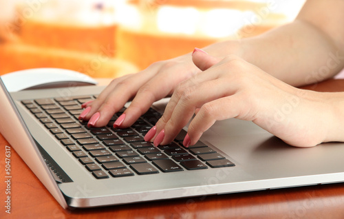 Photo: Female hands writing on laptop, on bright background Female hands writing on laptop, on bright background