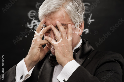 Photo: Bad Investment concept. Sad business man with currency symbols. Bad Investment concept. Sad business man with currency symbols.