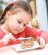 Little girl is eating cake in parlor