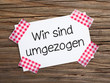 Klebestreifenzettel auf Holz WIR SIND UMGEZOGEN