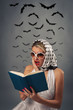 Scared retro woman reading book with bats silhouettes
