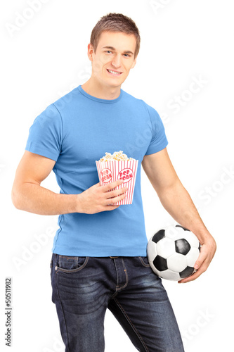 Photo: Male sports fan holding a football and popcorn box Male sports fan holding a football and popcorn box