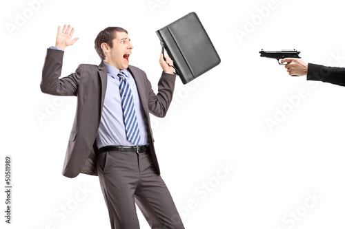 Photo: Scared businessman from a hand holding a gun Scared businessman from a hand holding a gun