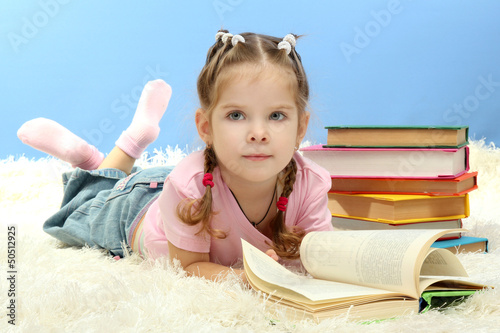 Photo: cute little girl with colorful books, on blue background cute little girl with colorful books, on blue background