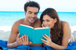 Couple Reading Book At The Beach