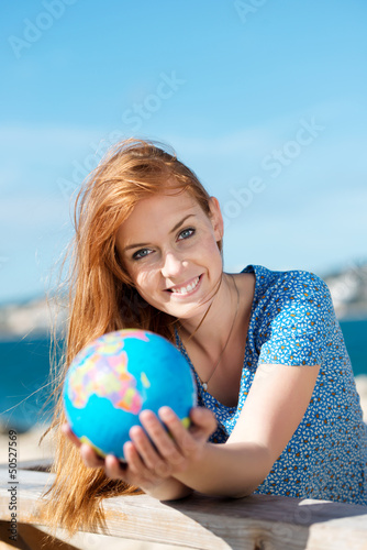 Photo: lachende junge frau mit globus am meer lachende junge frau mit globus am meer
