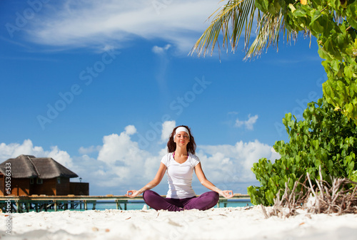 Photo: Pretty woman doing yoga exercises on the tropical beach Pretty woman doing yoga exercises on the tropical beach