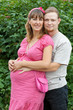 a happy young pregnant woman with her husband resting in a park