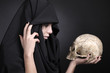Scary woman with a pale face with human cranium.