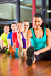 Group of people and instructor in gym stretching