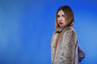 portrait of young woman in fur blue background