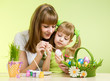 Photo: mother and child girl paint easter eggs over green background mother and child girl paint easter eggs over green background