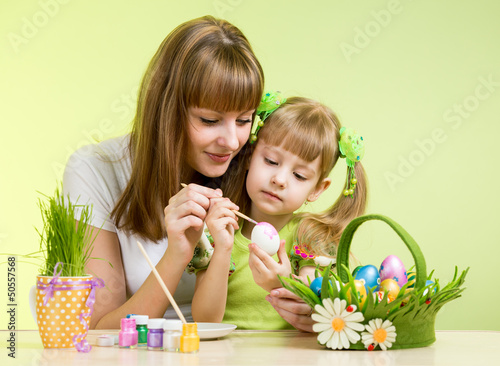 Photo: mother and child girl paint easter eggs over green background mother and child girl paint easter eggs over green background