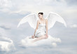 Beautiful young woman as angel sitting on a cloud