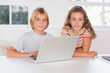 Photo: Two children looking at the camera with laptop Two children looking at the camera with laptop