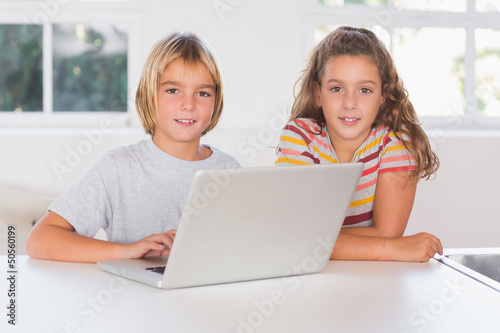 Photo: Two children looking at the camera with laptop Two children looking at the camera with laptop