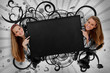 Girls pointing to black copy space with artistic swirl frame