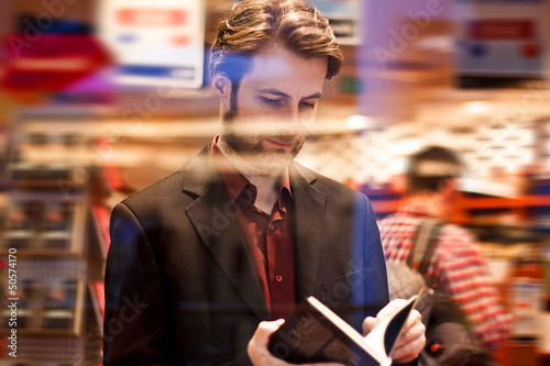 Photo: Forty years old man reading a book inside bookstore Forty years old man reading a book inside bookstore