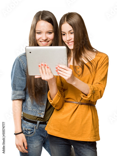 Photo: Teen girls sharing a tablet computer. Teen girls sharing a tablet computer.