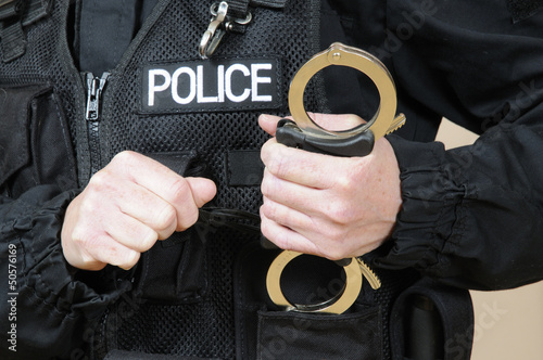 Photo: Police officer holding handcuffs Police officer holding handcuffs