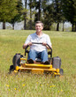 Senior man on zero turn lawn mower on turf