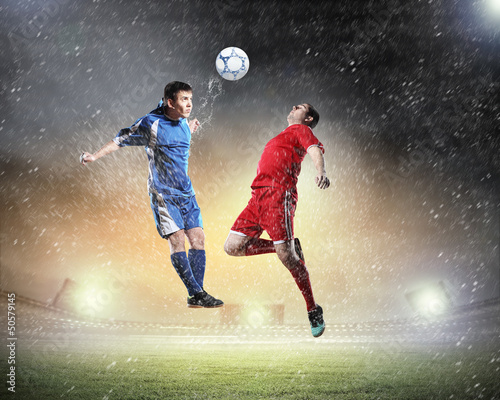 Photo: two football players striking the ball two football players striking the ball