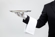 Waiter holding empty silver tray over gray background