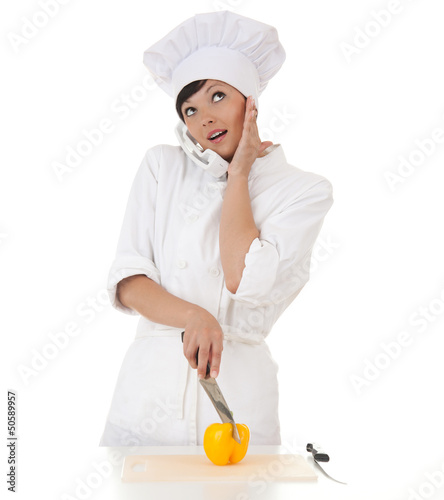 Photo: surprised female cook cutting paprika and speaking on the phone surprised female cook cutting paprika and speaking on the phone