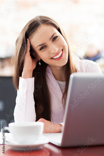 Photo: Young woman using laptop in cafe Young woman using laptop in cafe