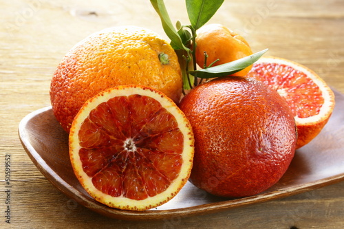 Photo: red (bloody) oranges on a wooden plate red (bloody) oranges on a wooden plate