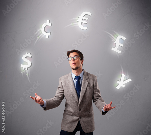 Photo: young man standing and juggling with currency icons young man standing and juggling with currency icons
