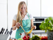 Young woman cooking in her kitchen, stiring in a pan