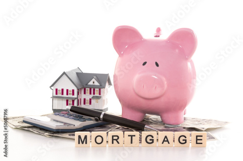 Photo: Piggy bank beside calculator miniature house and mortgage spelle Piggy bank beside calculator miniature house and mortgage spelle