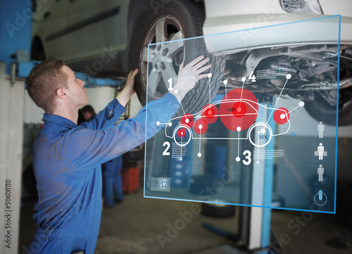 Photo: Mechanic checking wheel of a car helped by interface Mechanic checking wheel of a car helped by interface