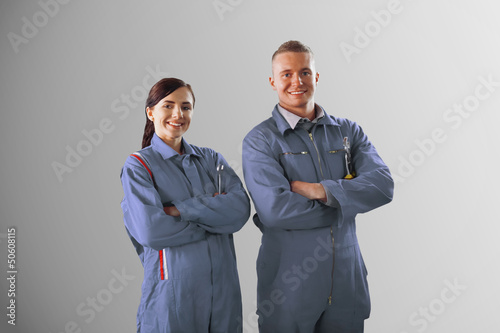 Photo: Two mechanics standing on grey background Two mechanics standing on grey background