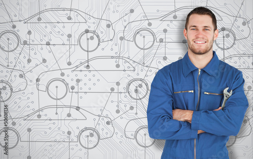 Photo: Young mechanic standing in front of cars background Young mechanic standing in front of cars background