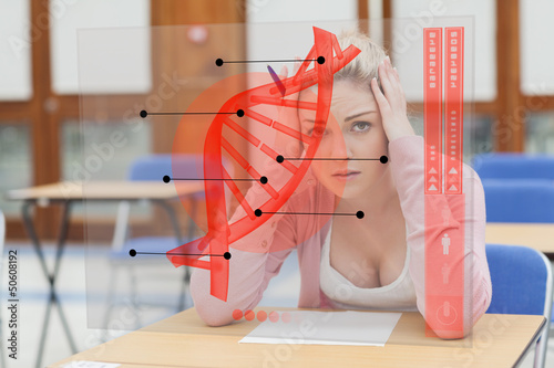 Photo: Blonde woman thinking hard while studying on futuristic interfac Blonde woman thinking hard while studying on futuristic interfac