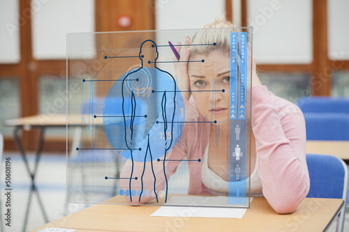 Photo: Blonde woman thinking hard while studying on interface with body Blonde woman thinking hard while studying on interface with body